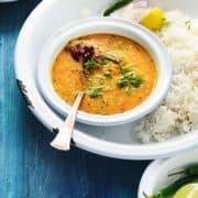 Hyderabadi Khatti Dal in white white bowl with rice on the side.