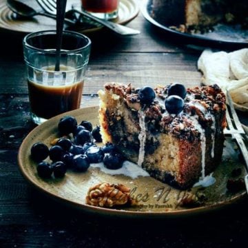 A slice of blueberry coffee cake served in brown plate with some blueberries and walnut