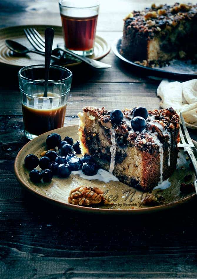 A slice of blueberry coffee cake served in brown plate with some blueberries and walnut