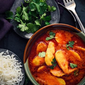 Arbi masala curry in ceramic bowl with rice bowl on the side.