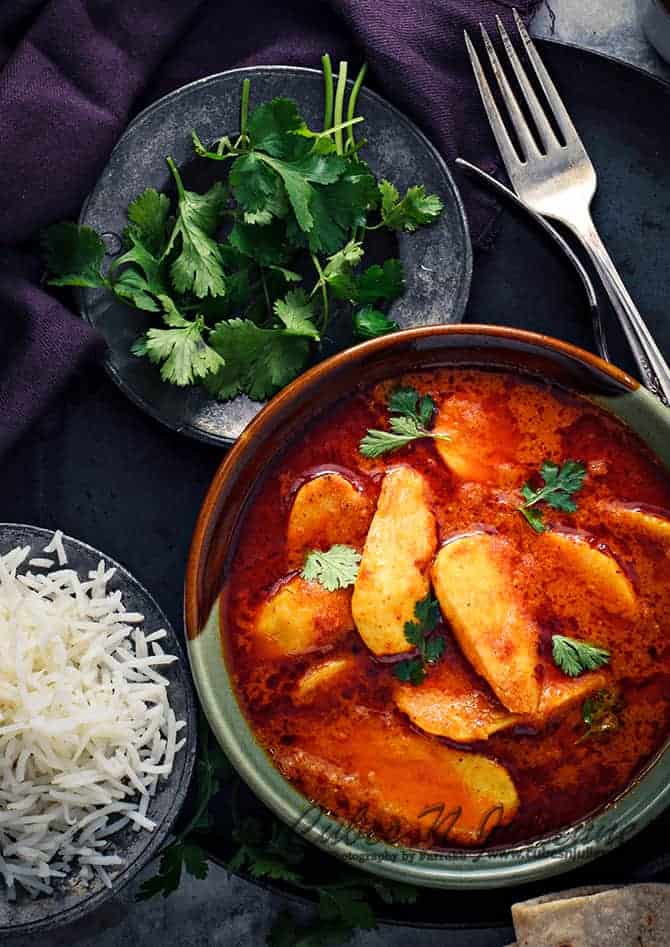 Arbi masala curry in ceramic bowl with rice bowl on the side.