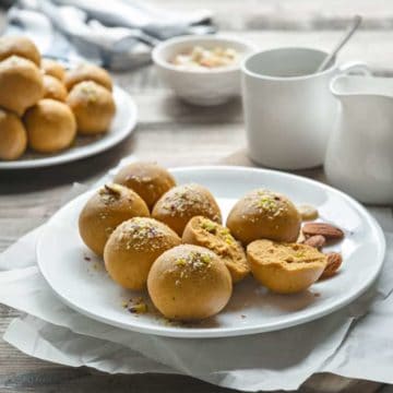 Besan Ladoo Sweet served on white plate, with one ladoo cut open.