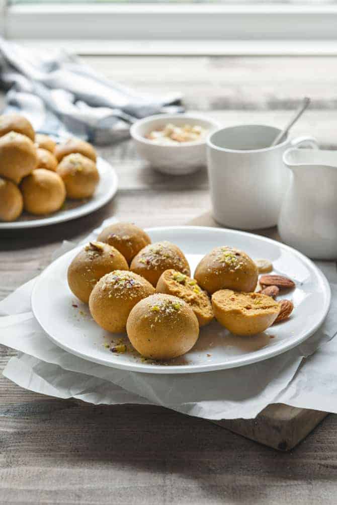 Close-Up shot of Besan Ladoo Sweet served on white plate, with one ladoo cut open.