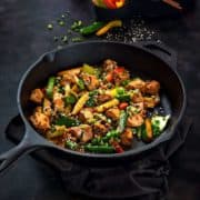 Chicken Stir Fry in a cast iron pan with some bell peppers at the back