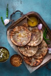 Bajre Ki roti served on brass tray with ghee and jaggery on the side.