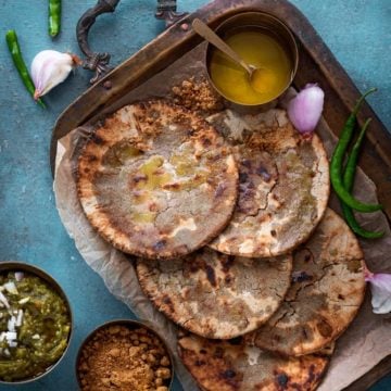 Bajre Ki roti served on brass tray with ghee and jaggery on the side.