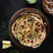 Tawa Garlic Naan on black plate with butter, salad and dal makhani on the side