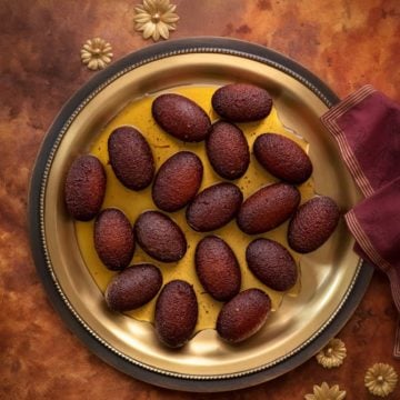 Overhead shot of Milk Powder Gulab Jamun served on traditional brass plate