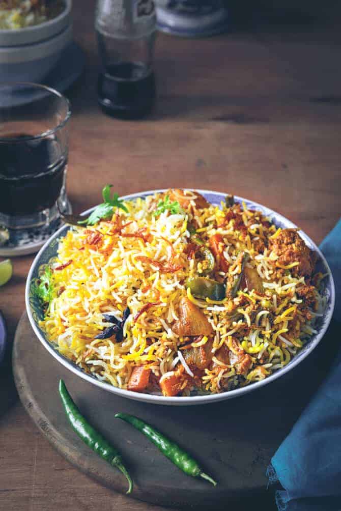 Hyderabadi vegetable Biryani served in blue bowl with soft drink on the side