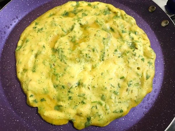 Batter poured on hot greased griddle to make moong dal chilla