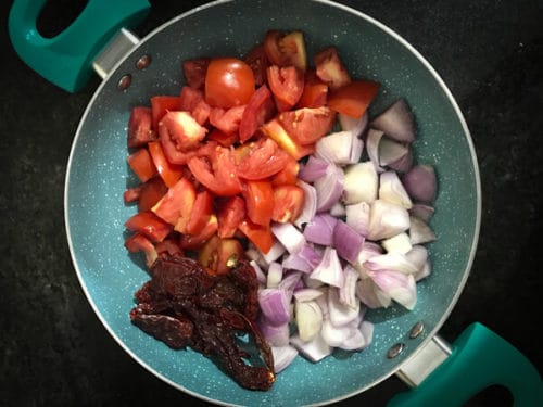  Making of onion tomato chutney - diced onions, tomato, and dried red Kashmiri chilli in a pan