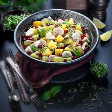 Indian style spiced mixed fruit chaat salad served in a large black bowl