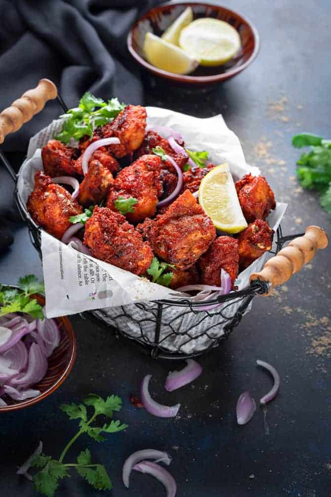 Spicy Chicken Fry bites served in basket with onions and lemon on the side