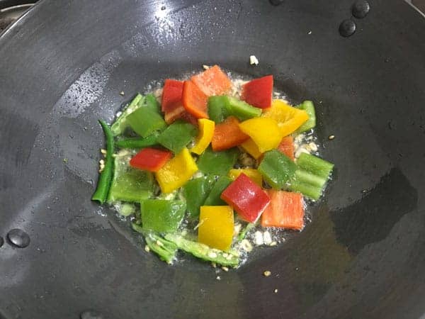 Cubed bell peppers added in wok.