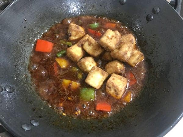 Fried Paneer cubes added in a wok for the making of chilli paneer.