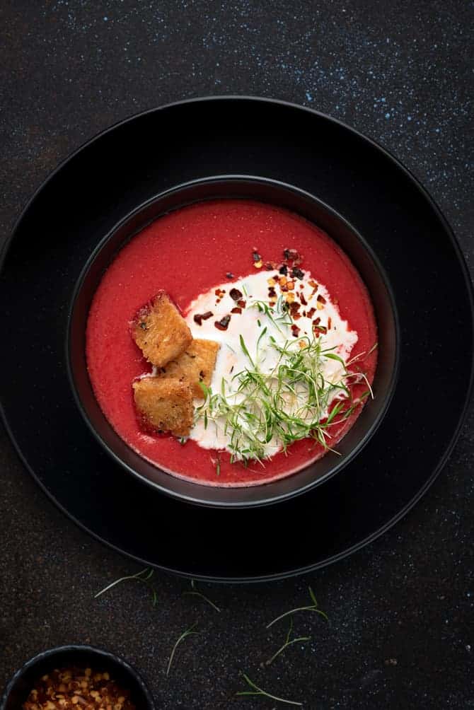 Close-up shot of beetroot tomato soup in black bowl