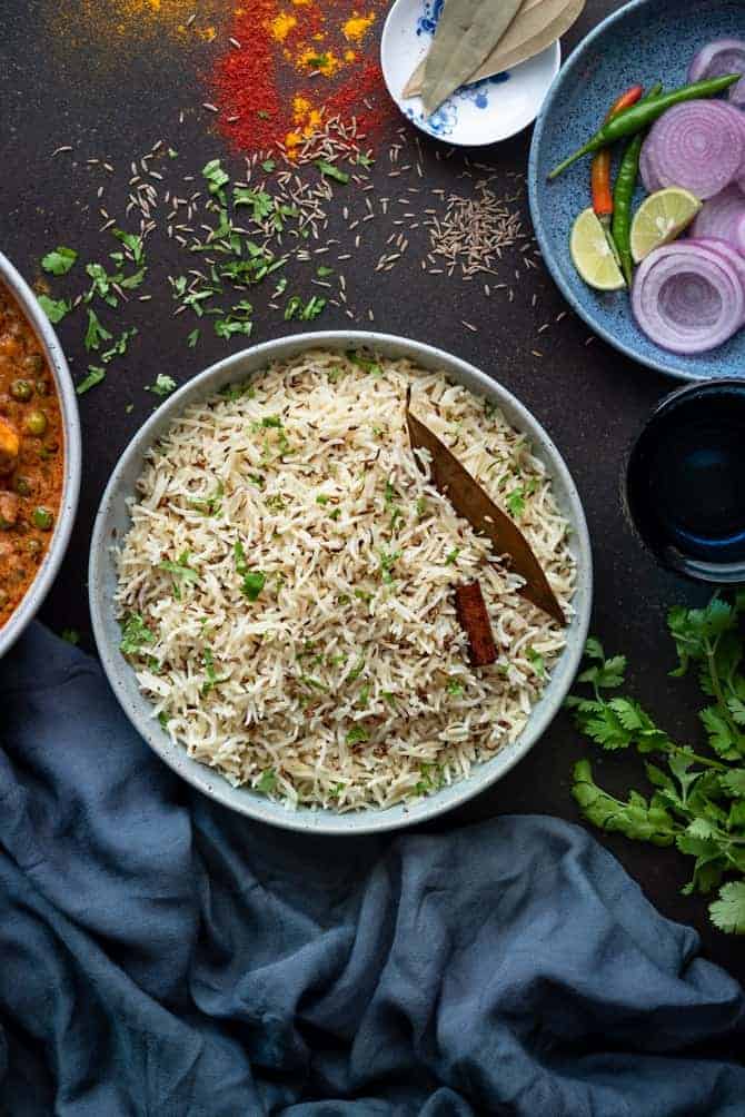 Jeera rice or Zeera rice served in large bowl with salad and curry on the side