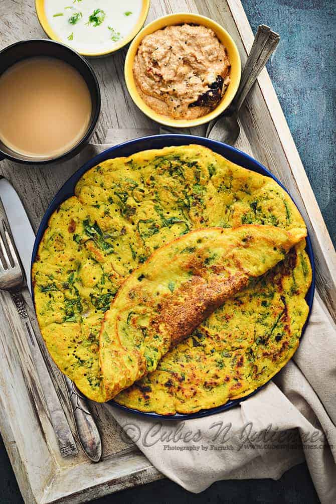 Palak Moong Dal Chilla on blue plate with chutney and tea on the side