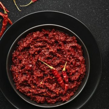 Close-up shot of red chili paste on black plate.