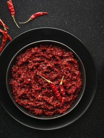 Close-up shot of red chili paste on black plate.