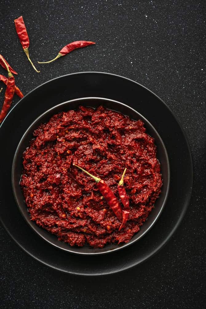 Close-up shot of red chili paste on black plate.