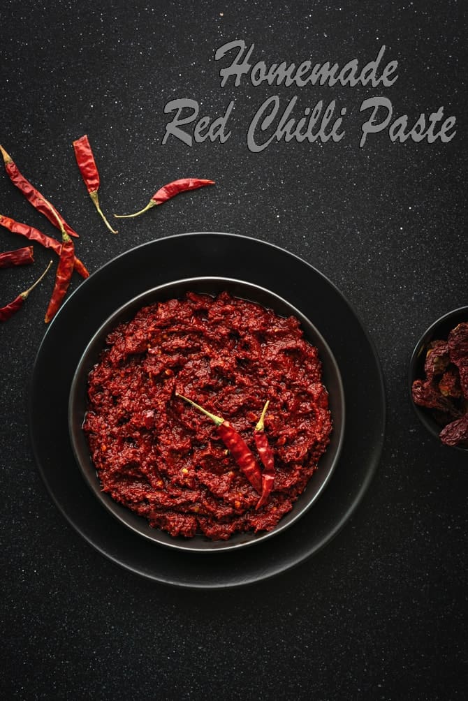 Homemade Chili paste on a black plate, dried chilies spread around