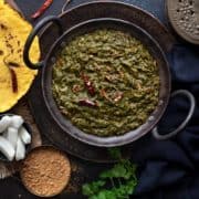 Punjabi Sarson ka Saag served in a kadhai (wok) with makki ki roti, radish and jaggery on the side