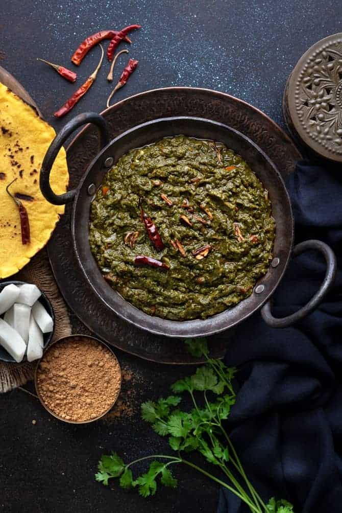 Punjabi Sarson ka Saag served in a kadhai (wok) with makki ki roti, radish and jaggery on the side