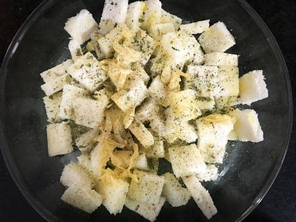 Garlic butter, herbs, salt, pepper and olive oil added to a bowl with cubed breads