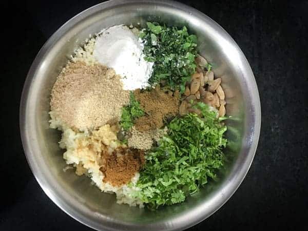 coriander, mint, cornflour, bread crumbs, ginger, raisins and spice powders added in a bowl