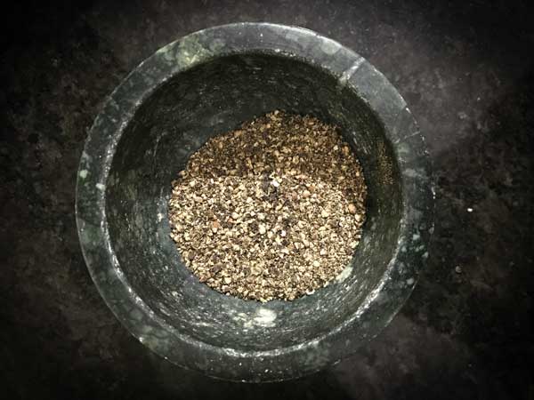 Black pepper ground coarsely in mortar pestle to make Chicken Kali Mirch recipe