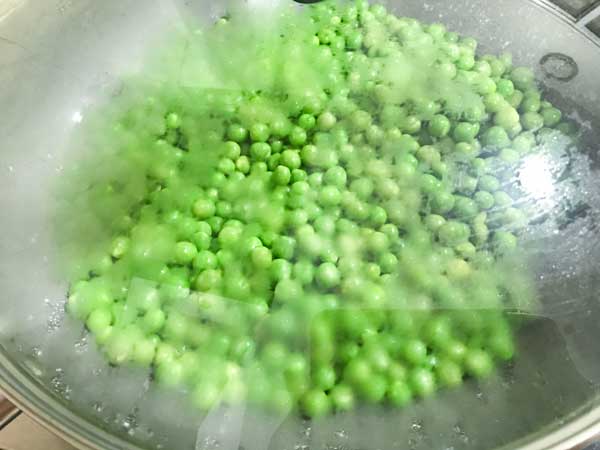 Green peas cooking in covered pan