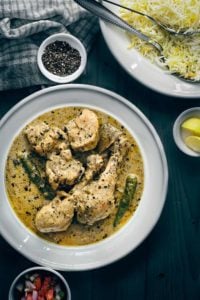 Overhead shot of chicken kali mirch in white plate with pulao the side.