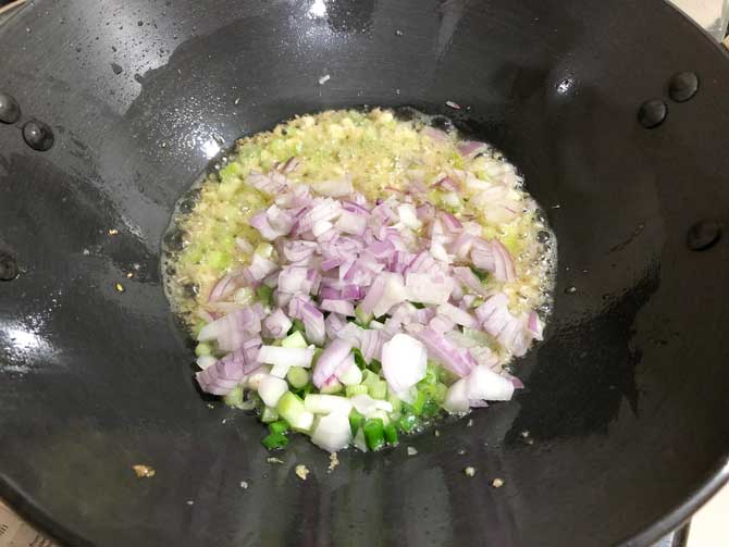 Chopped spring onion whites and onions added in wok