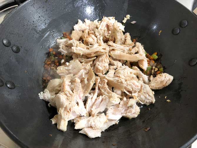 Crushed pepper and shredded chicken added in wok