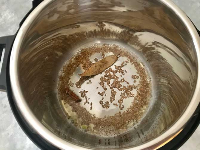 Cumin seeds, cinnamon, cardamom, bay leaf added in the hot oil in Instant pot