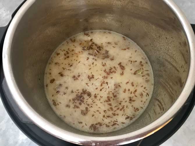 Strained rice, salt and water added in instant pot to make jeera rice