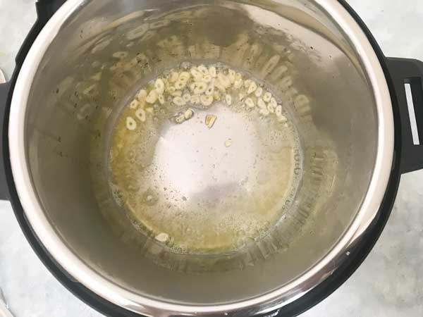Sliced garlic added in hot oil butter mixture in the Instant pot
