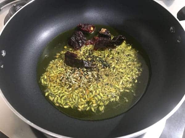 Red chilies, cumin, fenugreek, fennel, nigella, mustard seeds added in hot oil in pan