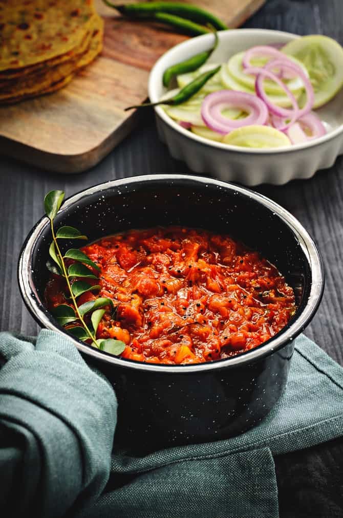 Andhra style tomato chutney recipe or Thakkali chutney in pan with salad at the back.