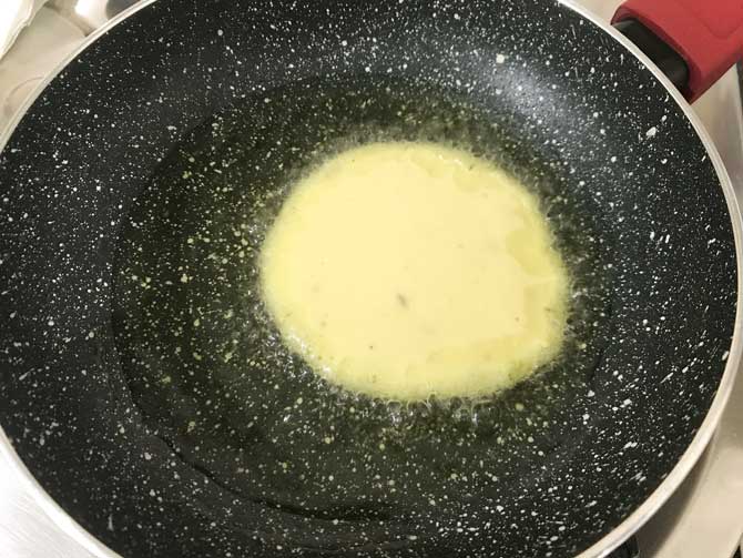 Malpua batter added in pan to fry in ghee on low heat