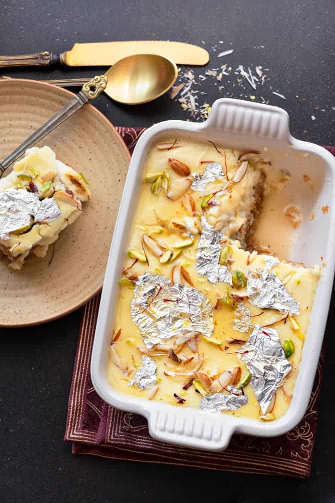 Overhead shot of Shahi Tukda in ceramic dish with a serving on brown plate on side.