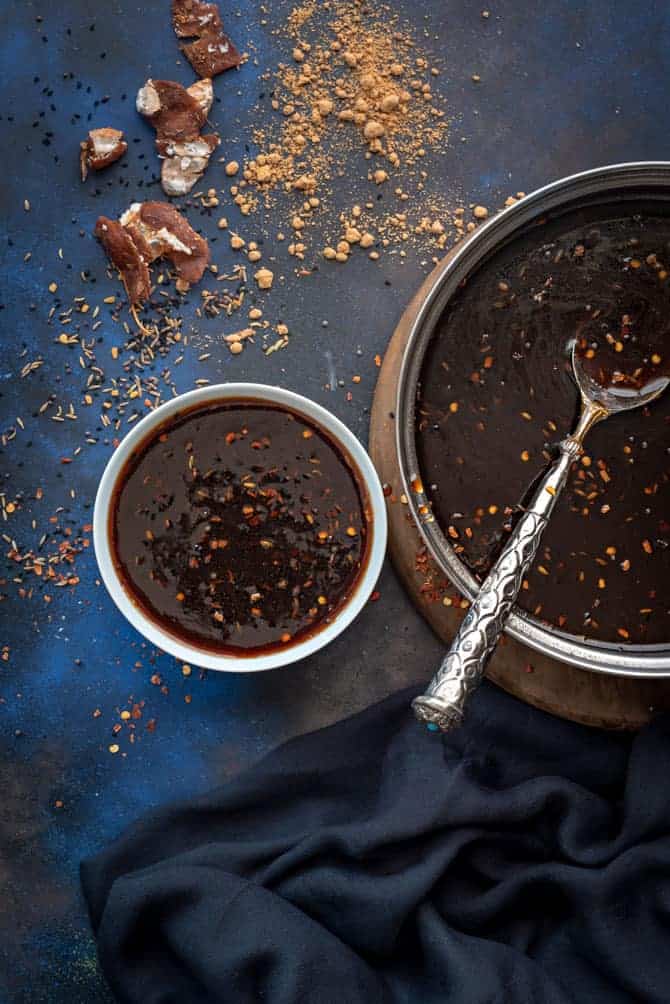 Overhead shot of tamarind chutney in white bowl and in pan with spoon in it.