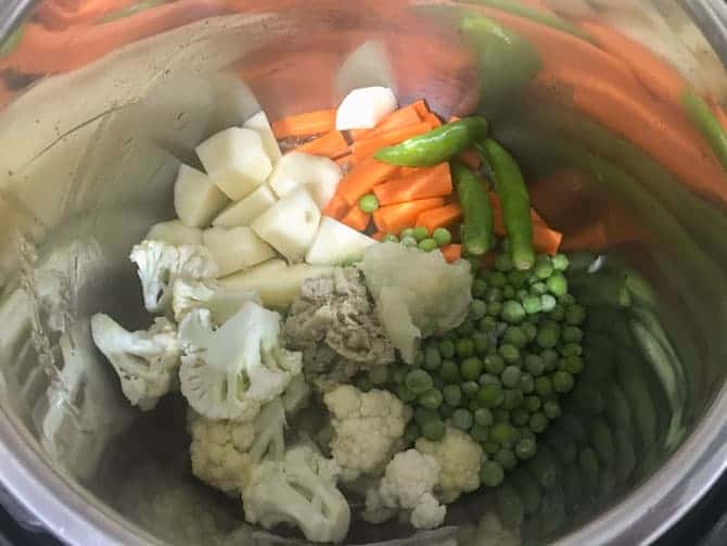 Cut vegetables, ginger and garlic paste, green chillies added in pot.