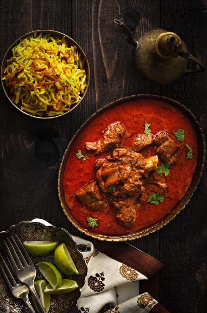 Awadhi mutton korma curry served in traditional oval brass bowl with rice on the side.