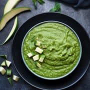 Green mango chutney or aam ki chutney in blue bowl with few raw mango pieces spread around