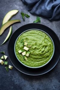 Green mango chutney or aam ki chutney in blue bowl with few raw mango pieces spread around