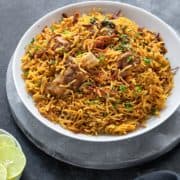 Instant pot Lamb Biryani served in white plate with lemon wedges on the side.