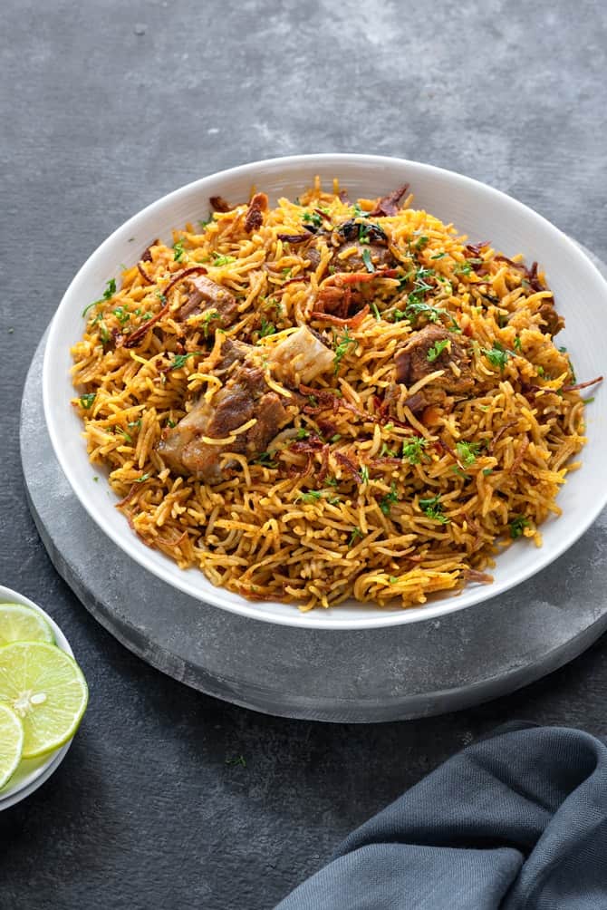 Instant pot Lamb Biryani served in white plate with lemon wedges on the side.