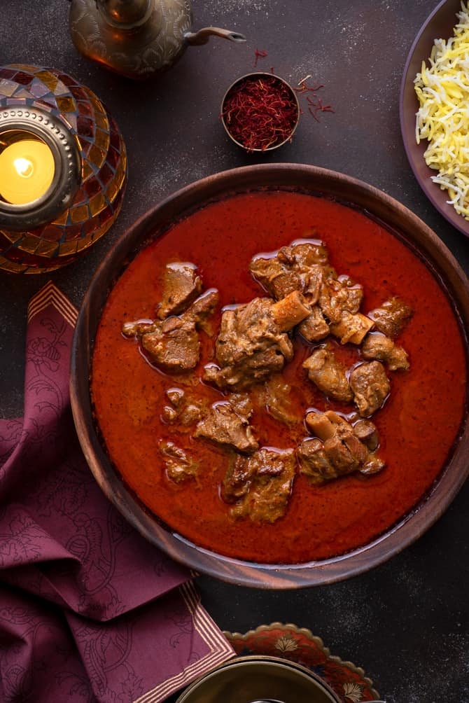 Traditional Awadhi Mutton Korma or lamb korma in wooden bowl with saffron rice on the side